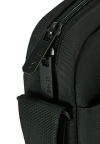 Czarna torba z tkaniny o teksturowanej powierzchni, z czarnym zamkiem i suwakiem. Solidna konstrukcja oraz widoczne mocowanie plecionej rączki.