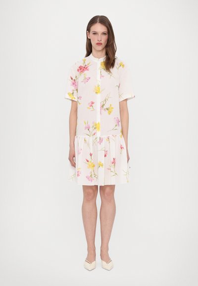 Blumen-Kurzarmkleid in Weiß mit rosa und gelben Blumen, mit rundem Halsausschnitt und rüschengesäumtem Saum. Leichter, strukturierter Stoff.