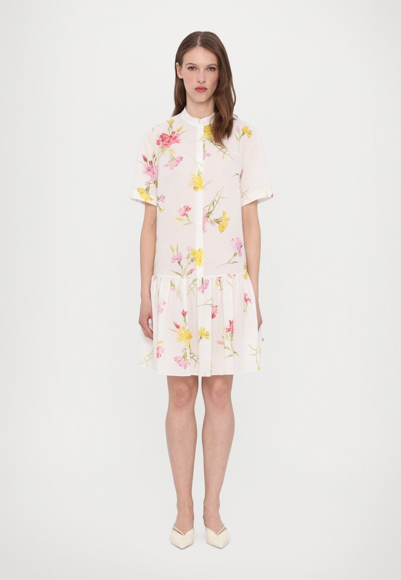 Floral short-sleeve dress in white with pink and yellow flowers, featuring a round neck and a ruffled hem. Lightweight textured fabric.