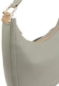 Grijze leren schoudertas met metalen hardware in goudkleur, een gladde textuur, gebogen vorm en een ritssluiting. Kenmerkt zich door gouden branding aan de basis.