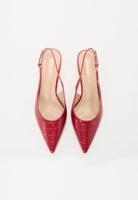 Røde slingback-hæle med spidse tæer og krokodillemønster. Har en guld spænde og en glat beige inderside. Brandnavnet "RAID" er synligt.