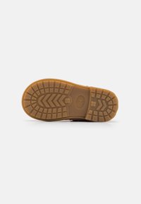 Rubber sole features a tread pattern with zigzag lines; light brown color; a circular number “24” embossed on the underside.