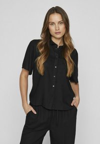 Black short-sleeve button-up shirt with a collar, made of lightweight fabric; features a relaxed fit and subtle texture.