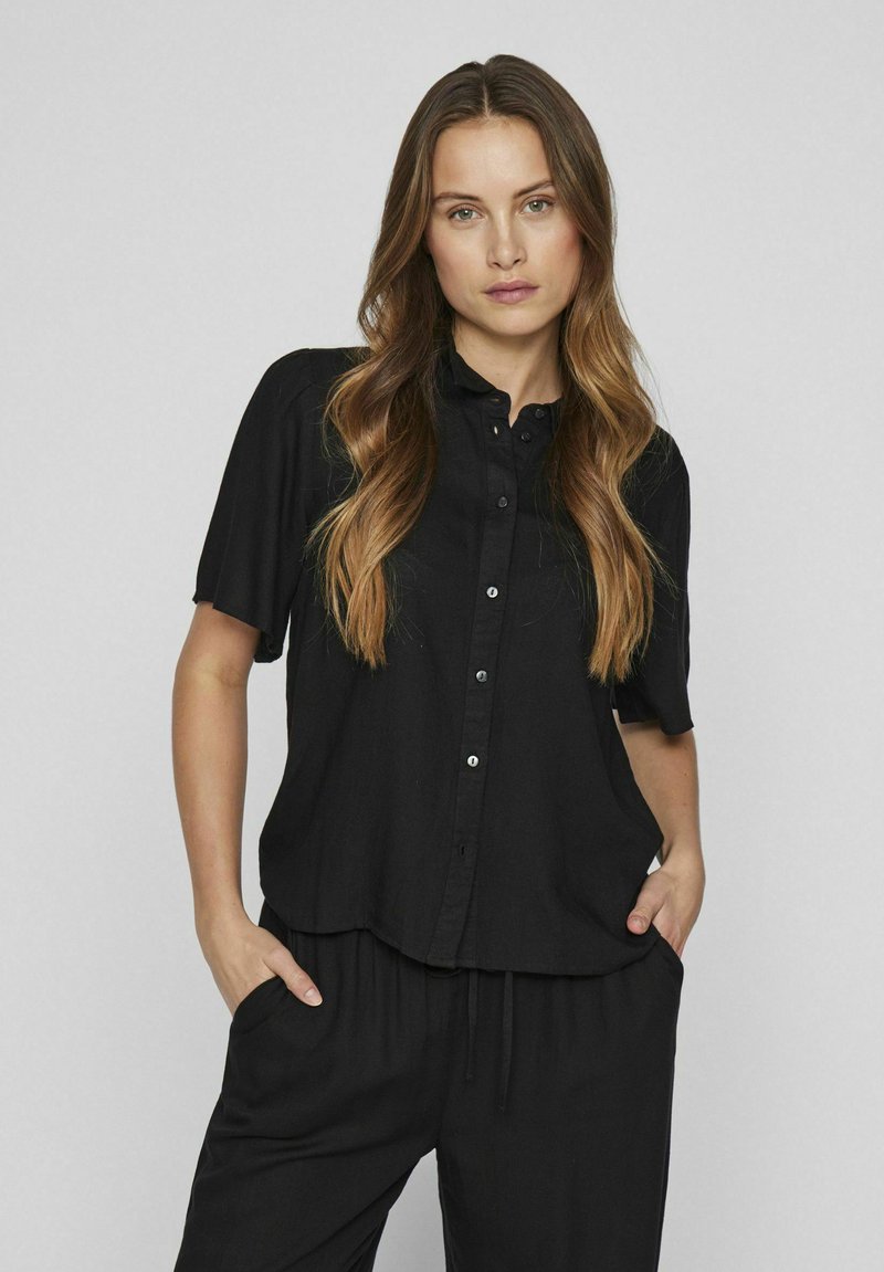 Black short-sleeve button-up shirt with a collar, made of lightweight fabric; features a relaxed fit and subtle texture.
