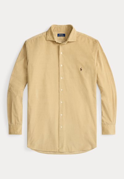 Camisa de veludo côr creme de mangas compridas, com fecho de botões à frente, colarinho e pequeno logótipo bordado no lado esquerdo do peito.