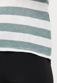 Stripet skjorte med hvite og teal horisontale striper, laget av lett stoff, med rett snitt og subtil tekstur.
