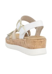 Beige and white sandal with a cork wedge sole, adjustable buckle, and soft suede accents. Features a textured footbed for comfort.