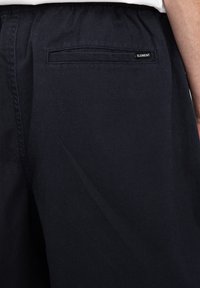 Mörkblå shorts i en bomullsblandning med elastisk midja, en bakficka med en lapp som säger "ELEMENT."