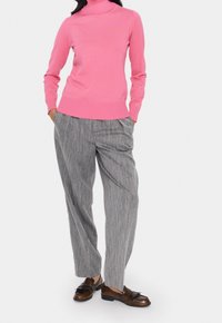 Tajta rosa polotröja, ribbade muddarna och nederkant, tillsammans med grå ränder vid vida byxor och bruna loafers.