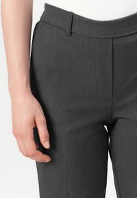 Pantalons tailleur gris foncé avec une texture lisse, devant plat et détail de pli subtil ; dotés d'une taille standard et d'ouvertures pour les poches.