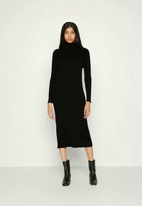 Fekete hosszú ujjú garbóruha, térd alá érő, testhezálló szabás, bordázott textúrával, fekete bokacsizmával párosítva.