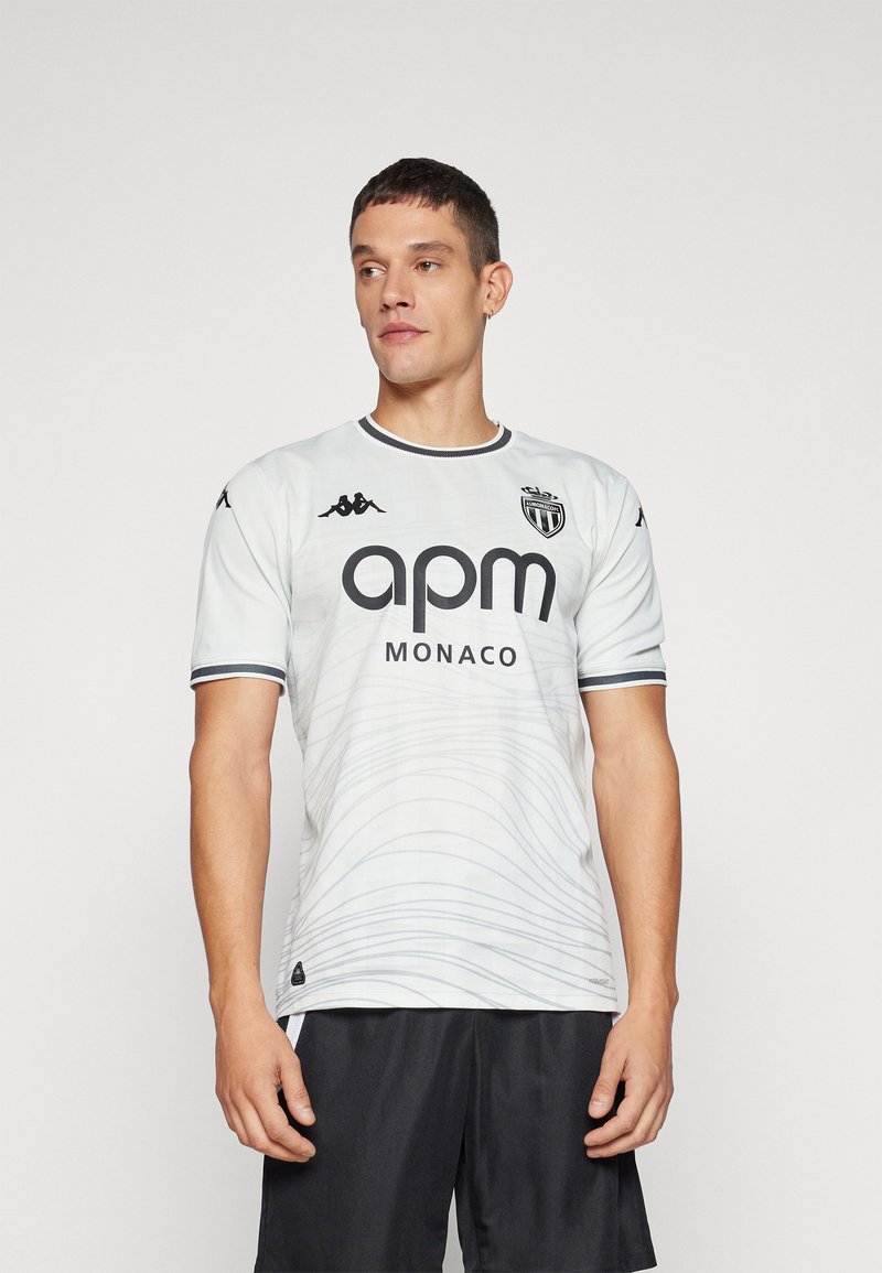 Witte voetbalshirt met korte mouwen, voorzien van een subtiele golfpatroon, zwarte accenten, groot "apm MONACO" logo, en Kappa merk op de mouwen.