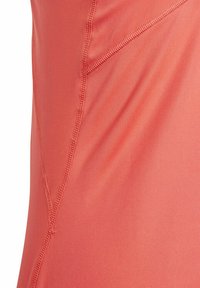 Koraal kleurig sporttop van soepel, rekbaar materiaal. Met platte naden en een subtiele glans. De snit benadrukt een aansluitend ontwerp.