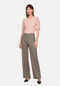 Light pink puff-sleeve top paired with wide-leg, leopard print trousers. Smooth texture; tailored fit. Black pointed-toe heels complete the look.