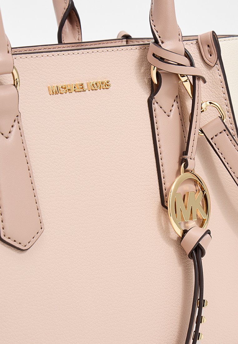 Beige Handtasche aus Leder mit goldener Hardware, ausgestattet mit einem Signaturlogo, verstellbarem Tragegurt und auffälliger Nahtführung an den Griffen.