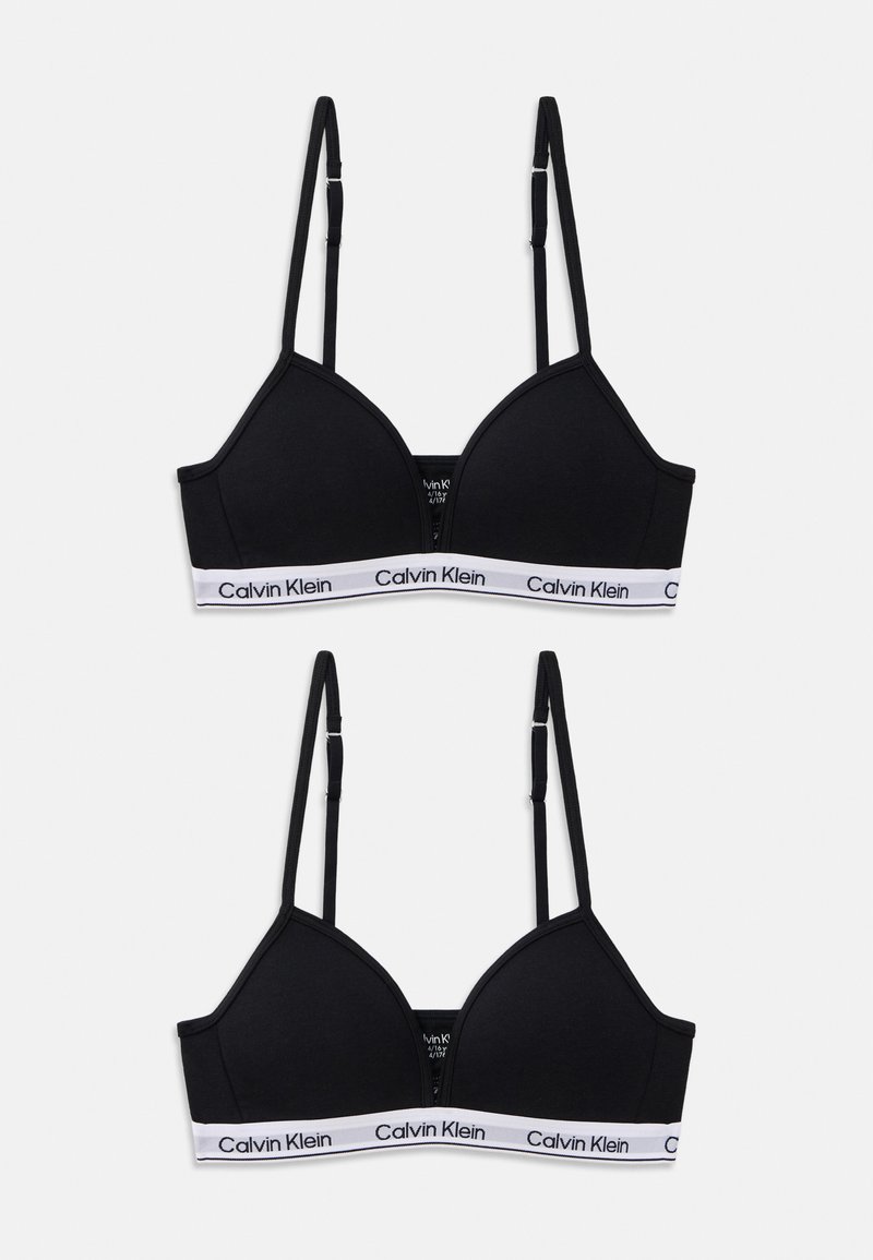 Svart bralette med justerbare tynne stropper, myk stoff, trekantet kopper, og en hvit Calvin Klein-logo band langs bunnen.