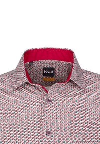 Camicia bianca con un motivo geometrico rosso e verde, bottoni viola e colletto interno a contrasto rosa. Etichetta con vestibilità moderna visibile.