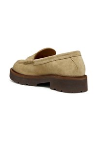 Mocasines de ante beige sin cordones con una gruesa suela de goma marrón, que presentan costuras detalladas y una parte superior elevada y texturizada.