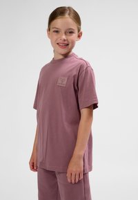 Kortärmad t-shirt med avslappnad passform i dov mauvefärgad bomull, med en liten präglad logotyp på bröstet och en klassisk rund halsringning.