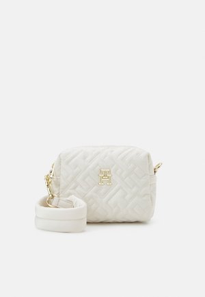 Klein wit doorgestikt schoudertasje met goudkleurig logo-embleem en afneembare gevoerde riem op een effen achtergrond.