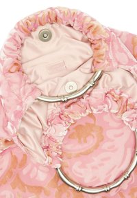 Różowa torebka z wzorzystego materiału, z metalowymi srebrnymi uchwytami w kształcie pierścieni i magnetycznym zapięciem na satynowym wykończeniu wnętrza.