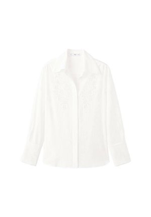 Biała koszula zapinana na guziki wykonana z lekkiego materiału, z długimi rękawami, klasycznym kołnierzykiem i haftowanymi zdobieniami na przodzie.