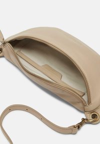 Borsa in pelle beige con texture morbida, chiusura con zip, tasca interna e tracolla removibile. Interno foderato in tessuto chiaro.