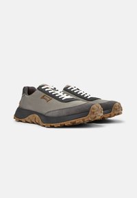Scarpe sportive grigie e nere con tomaia in tessuto testurizzato, suola in gomma e lacci bianchi a contrasto. Presentano un logo sul lato e una suola robusta.