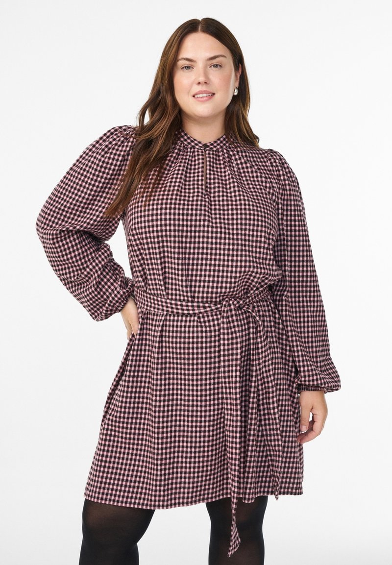 Sukienka w kratę z bordowo-białej tkaniny, z wysokim kołnierzem, talią dopasowaną paskiem, długimi rękawami i wiązanym paskiem.