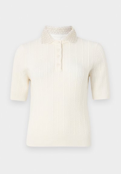 Lühikeste varrukatega kudumisest meeldiv polo-sweater heleses värvitoonis, millel on sooniktekstuur ja pärlitega kaunistatud krae. Tal on nööpkinnipead ees.