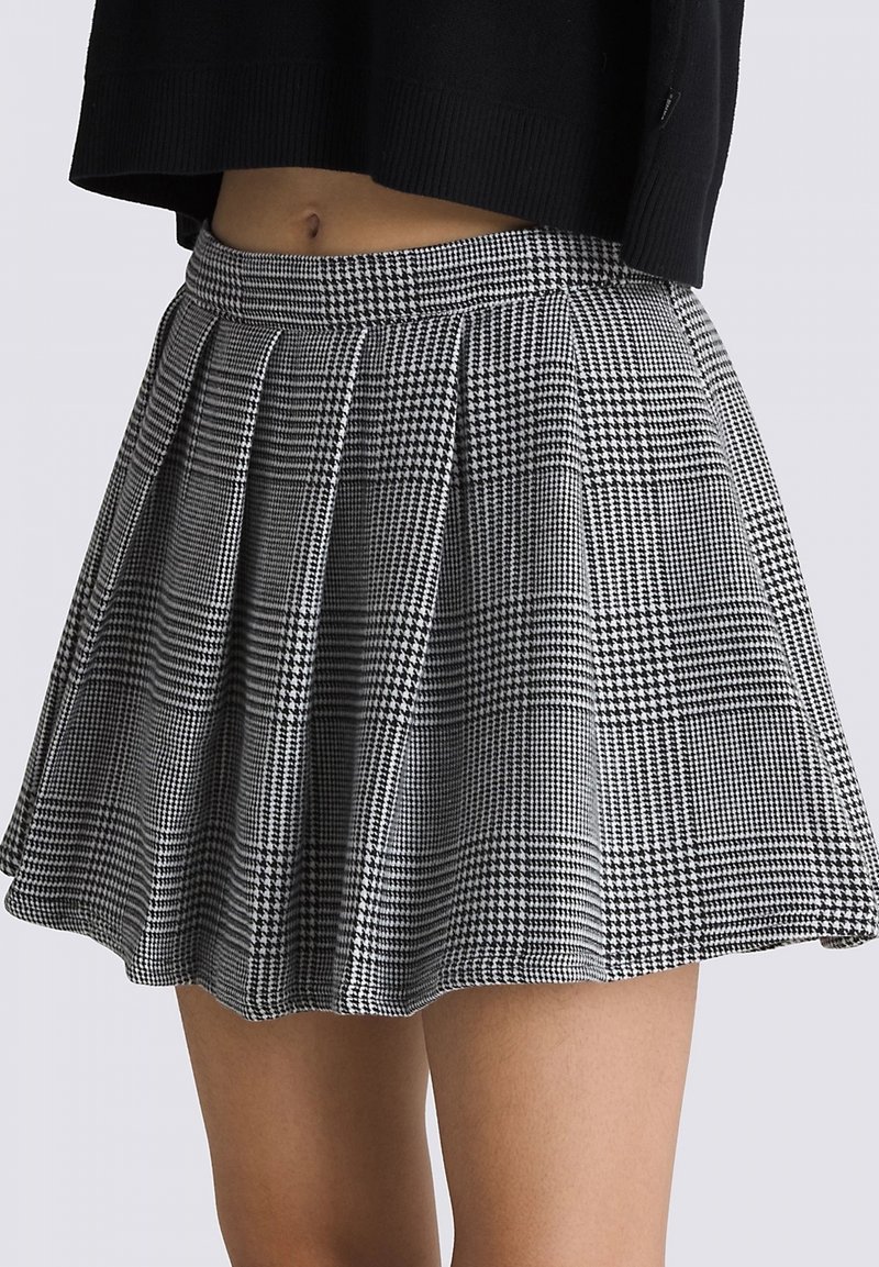 Falda plisada de cuadros en blanco y negro con una cinturilla ajustada, hasta la rodilla, hecha de un tejido texturizado que presenta patrones de pata de gallo y cuadros.