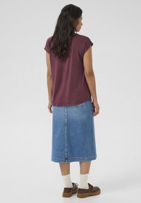 Haut bordeaux à manches courtes associé à une jupe midi en denim bleu clair. Comprend une coupe droite, un ourlet effiloché et des chaussures à lacets brunes.