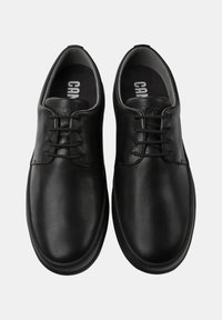 Scarpe in pelle nera con una texture liscia, punta arrotondata e un classico design con lacci. Include sole interne con marchio.