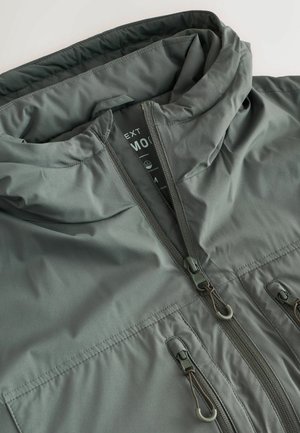 Grau wasserdichte Jacke mit Kapuze, ausgestattet mit einem durchgehenden Reißverschluss, zwei Fronttaschen und verstellbaren Kordeln. Glatte Textur und matte Oberfläche.