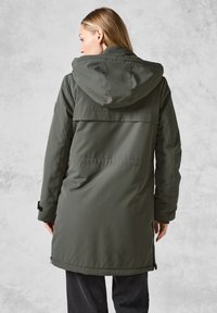 Parka lunga con cappuccio in tessuto verde scuro con una texture liscia. Presenta un design a yoke, tasche laterali con zip e chiusure regolabili ai polsi.