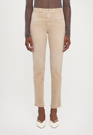 Beige, slim-fit jeans with a mid-rise waist, featuring front pockets and contrasting stitching. Soft denim material with a slightly distressed hem.