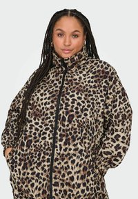Jakna s leopard uzorkom na zatvaranje s patentnim zatvaračem u bež i smešnim tonovima, s visokim ovratnikom, bočnim džepovima i opuštenim krojem. Mekana tekstura i lagani dizajn.