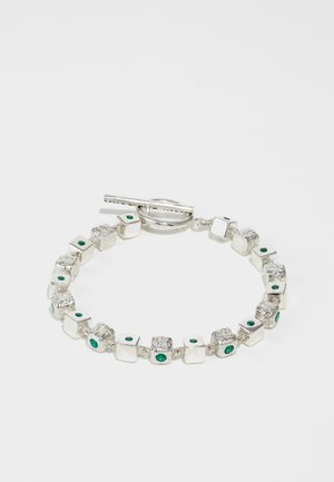 Srebrna narukvica s teksturiranim i glatkim kvadratnim karikama, ukrašena zelenim draguljima. Ima kopču na preklop za sigurno zatvaranje.