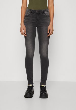 Sort denim skinny jeans med en falmet finish, fem-lomme design og let stræk. Kombineret med sorte sneakers med gule detaljer.