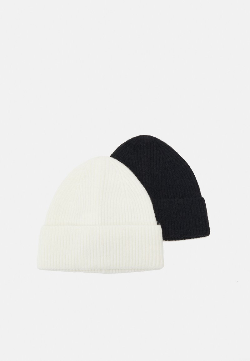 Two ribbed knit beanie hats: one white and one black. Both have a folded cuff and a soft, textured fabric.