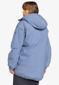 Veste rembourrée bleu clair avec une capuche, dotée de poignets élastiques et de poches latérales. Le tissu a une texture lisse et est résistant à l'eau.