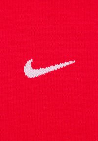 Sfondo in tessuto rosso con il logo Nike swoosh bianco al centro, caratterizzato da una texture liscia e un design semplice e curvo.