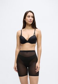 Soutien preto acolchoado com alças finas, combinado com calções modeladores pretos altos e transparentes, apresentando uma cintura lisa e design sem costuras.