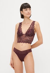 Burgundijas mežģīņu bralete ar viļņotām malām un ziedu rakstiem, pārī ar atbilstošu mežģīņu buxes. Mīkstas, delikātas tekstūras.