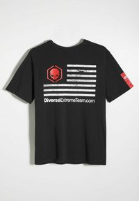 Czarny t-shirt z wyblakłym motywem amerykańskiej flagi, z czerwonym logo czaszki oraz białym tekstem "DiverseExtremeTeam.com". Krótkie rękawy.
