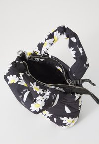 Geantă florală neagră cu margarete albe și accente galbene, material din țesătură, închidere cu fermoar și un design al mânerului răsucit.