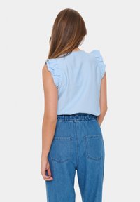 Ljusblå topp med volangärmar, parat med högmidjade denimbyxor med två bakfickor och en avslappnad passform.