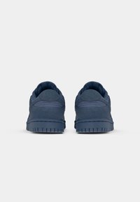 Nike'i tossud tumesinises, valmistatud tekstureeritud seemisnahast, sujuva kandviguriga. Omab kummist tallat, millel on haardemuster.