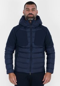Giubbotto trapuntato blu navy con cappuccio, dotato di zip frontale, due grandi tasche sul petto e un design isolato e testurizzato.