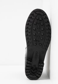 Semelle d'une chaussure Rieker noire avec des crampons profonds, motifs losange et fleur de lys, taille 37 marquée sur la semelle.